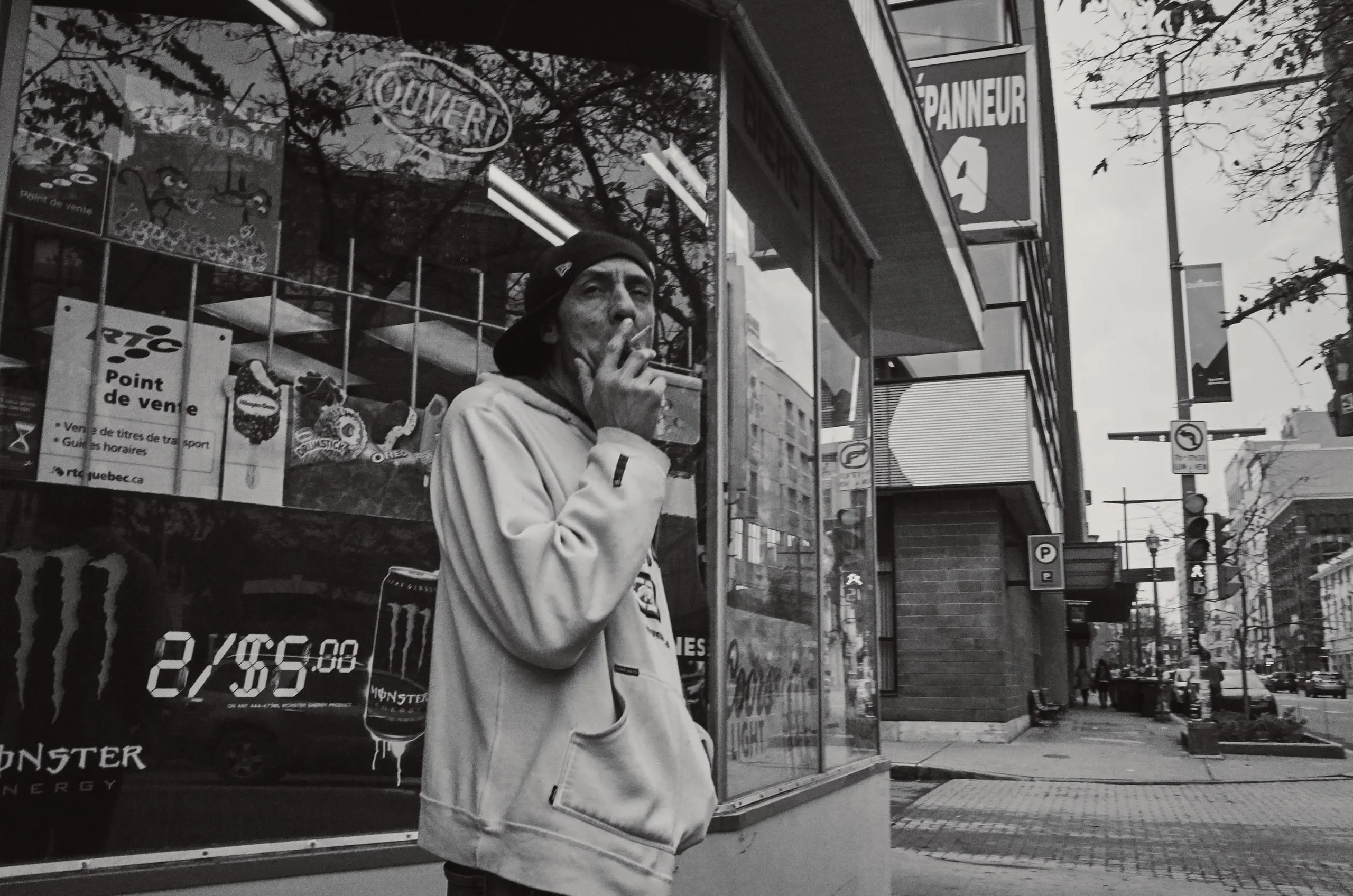 Homme fumant une cigarette devant un dépanneur.