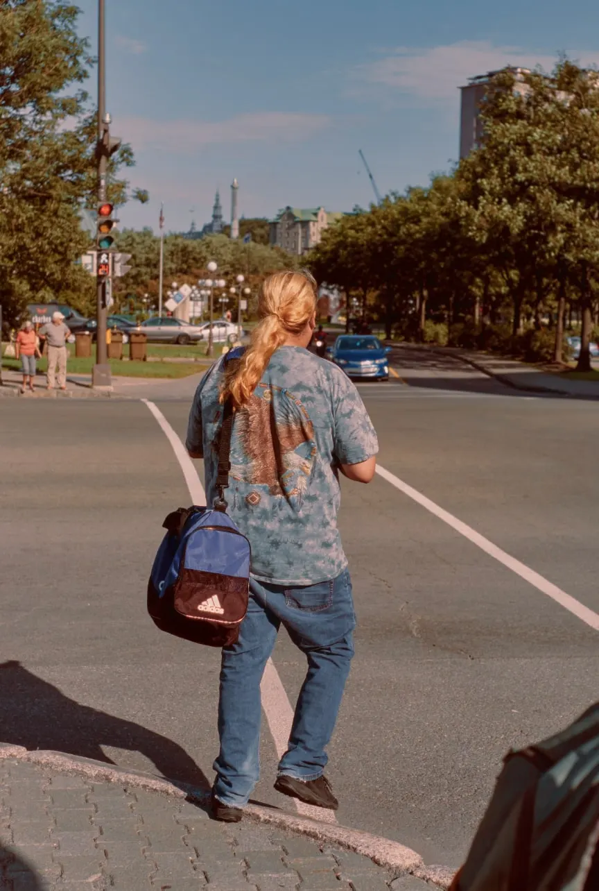 Jeune homme avec des cheveux longs, teint blond et un tee-shirt d'aigle et un sac de sport. 