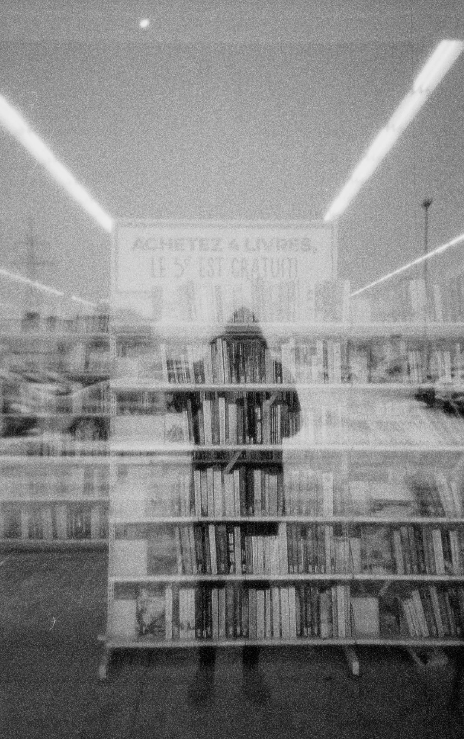Homme regardant une vitrine où on y voit des livres 