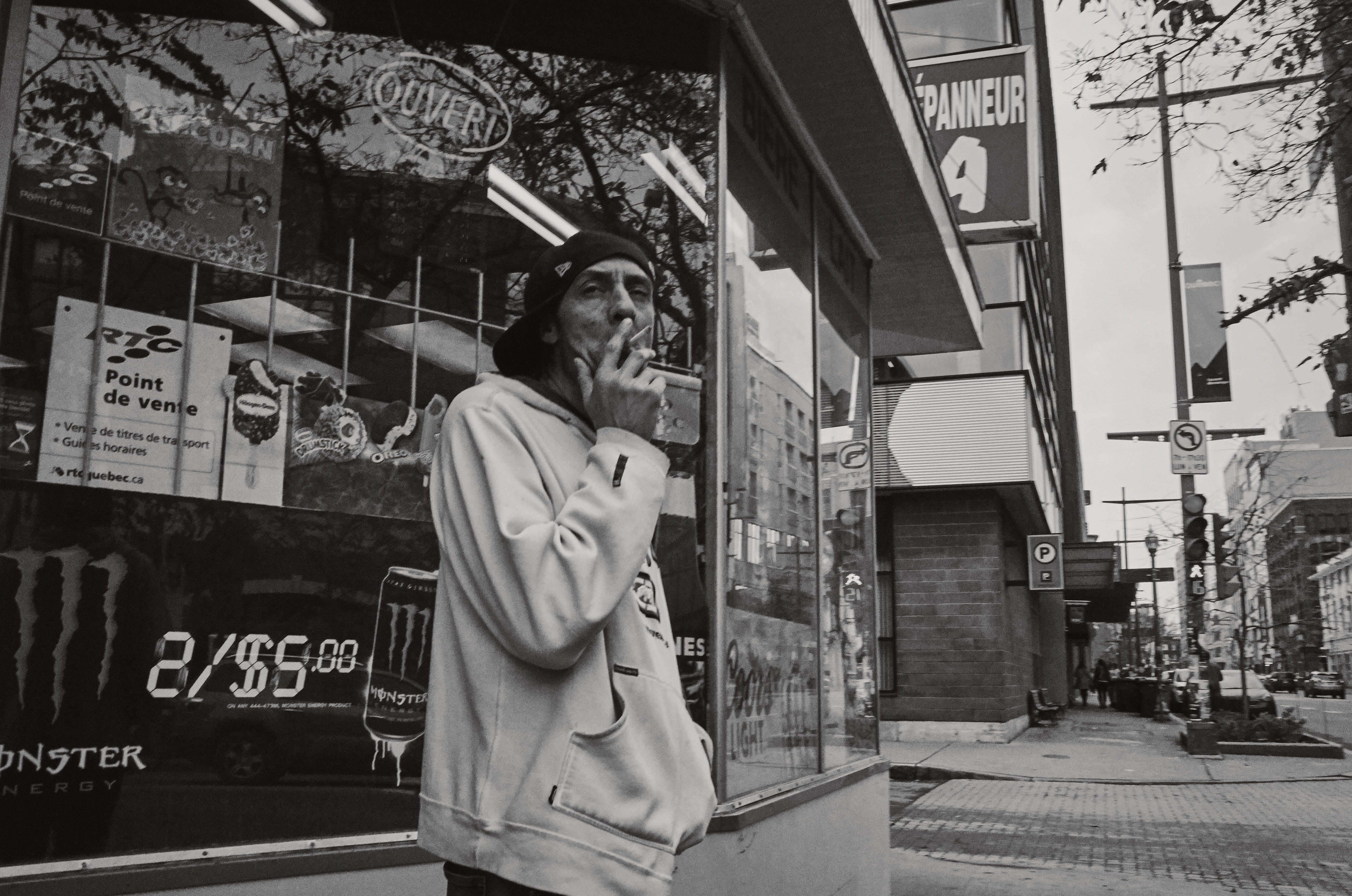 Homme fumant une cigarette devant un dépanneur.