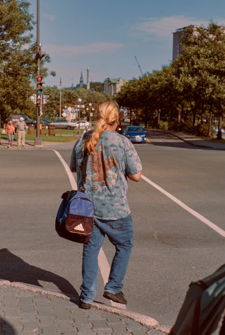Jeune homme avec des cheveux longs, teint blond et un tee-shirt d'aigle et un sac de sport. 